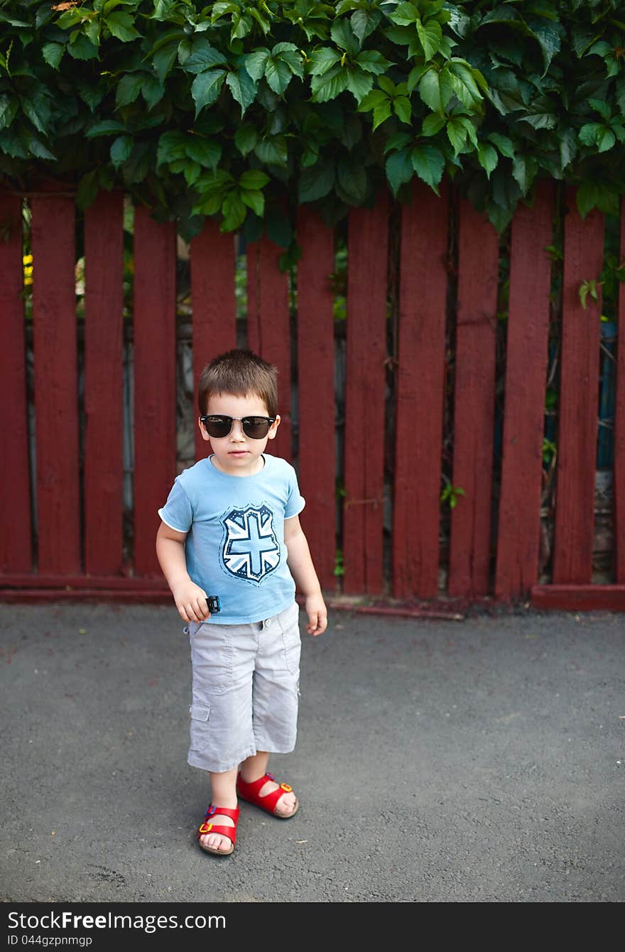 Cool boy wearing sunglasses, standing outdoors on sidewalk. Cool boy wearing sunglasses, standing outdoors on sidewalk