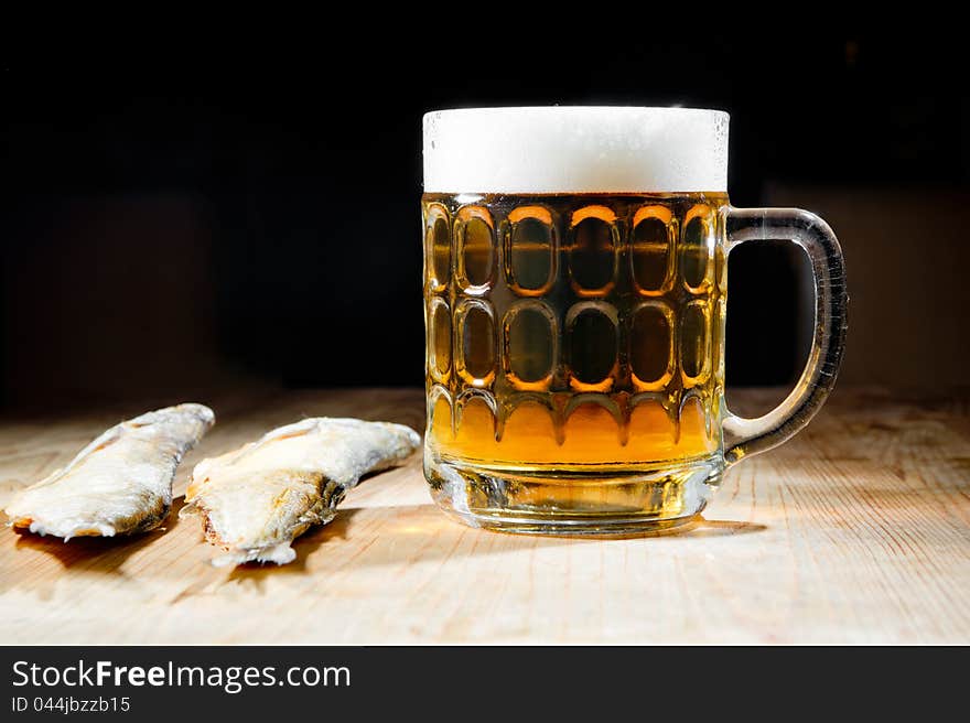 Beer with dry salty fish on a dark background