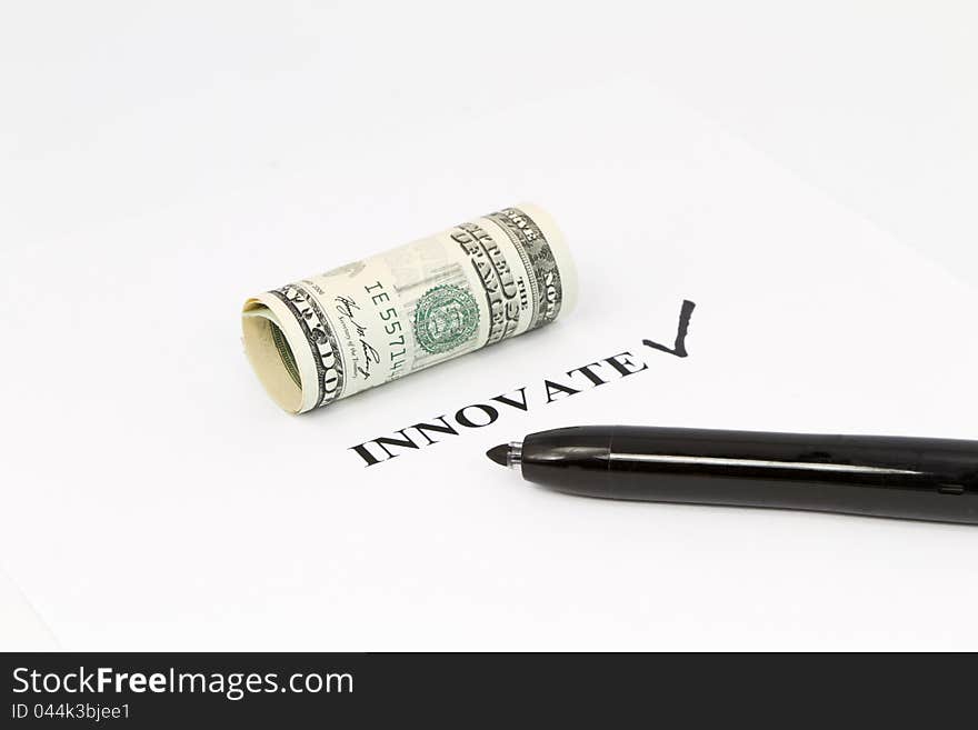 The word, innovate, is printed out with a black check next to it and rolled US currency above.  Black felt tip pen is on the right;