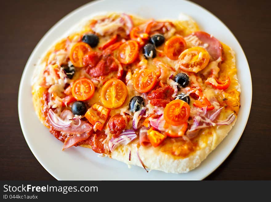 A pizza coated with salami, olives, onions and tomatos. A pizza coated with salami, olives, onions and tomatos