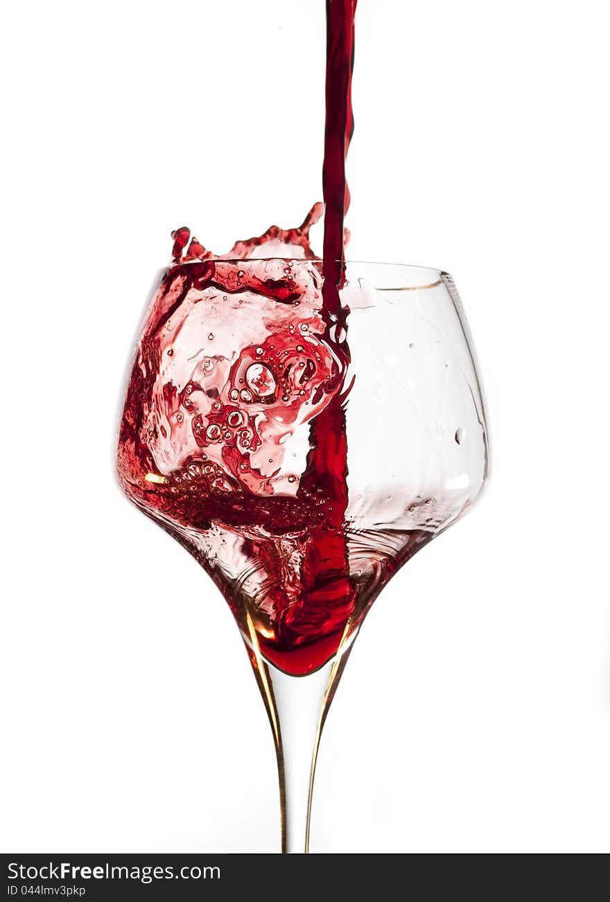 Red wine pouring into glass, isolated on white background