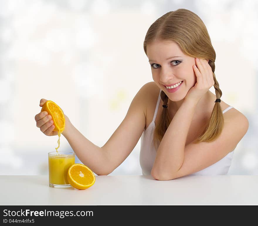 Beautiful girl squeezes the juice from the orange