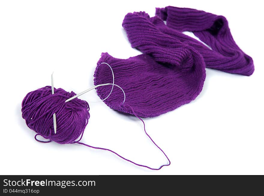 Close-up photos of the coil of purple yarn with knitting needles on the white background. Close-up photos of the coil of purple yarn with knitting needles on the white background