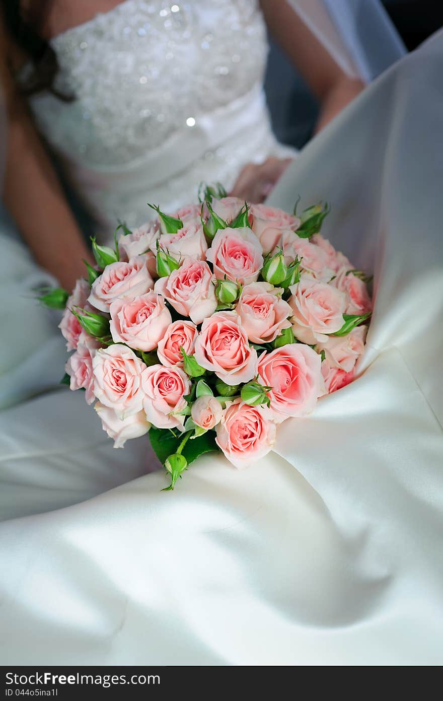 Bride in white dress holding bouquet of roses