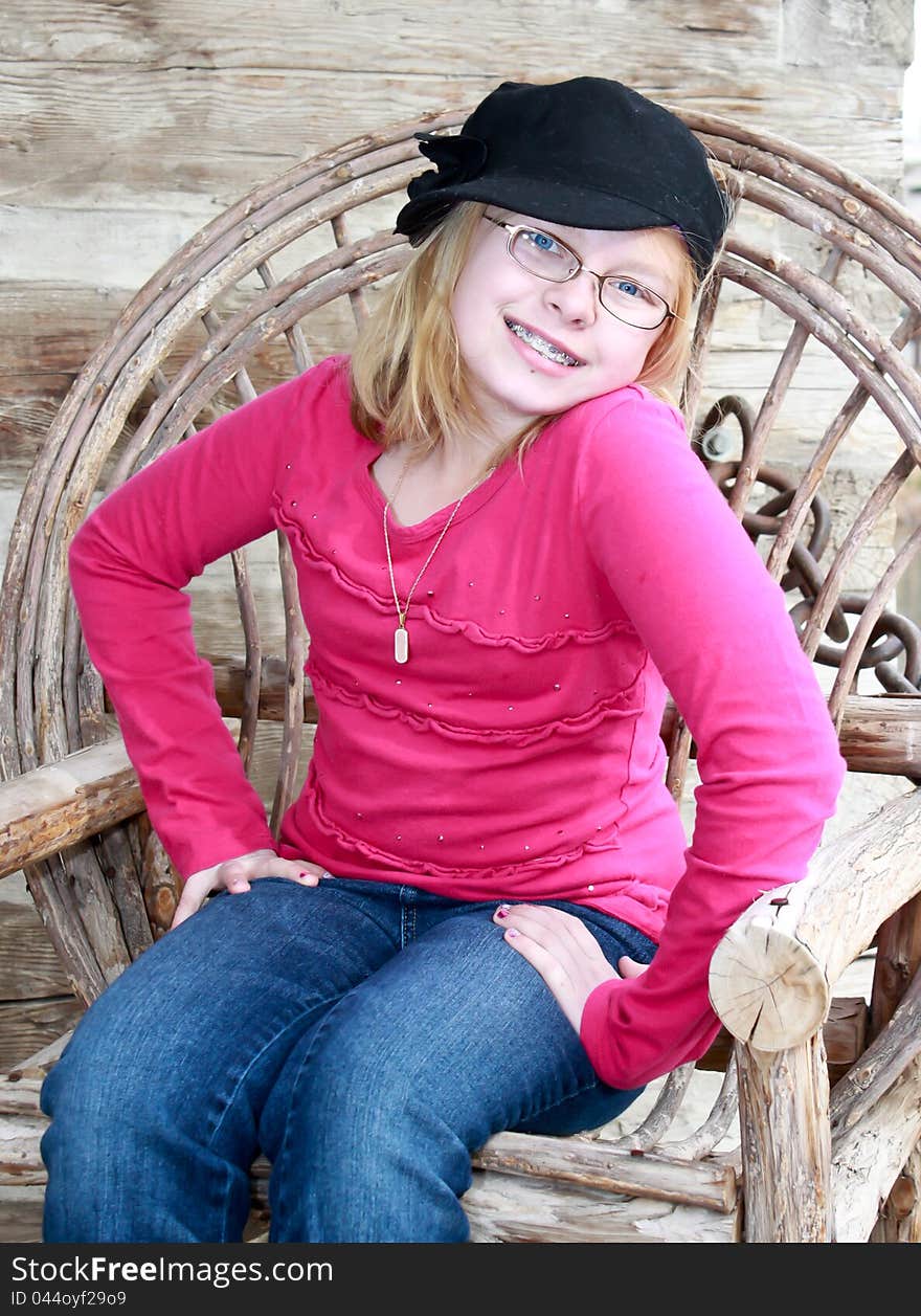 Image of a teenager sitting in a old wooden chair, posing and smiling. Image of a teenager sitting in a old wooden chair, posing and smiling