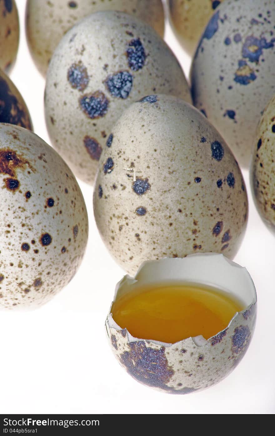 Quail eggs with one open on a white background