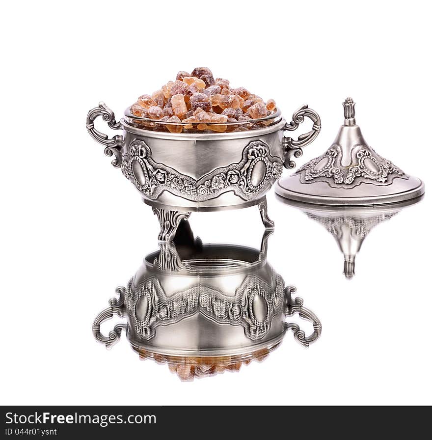 Brown sugar, in metal sugar bowl, white background ,reflection