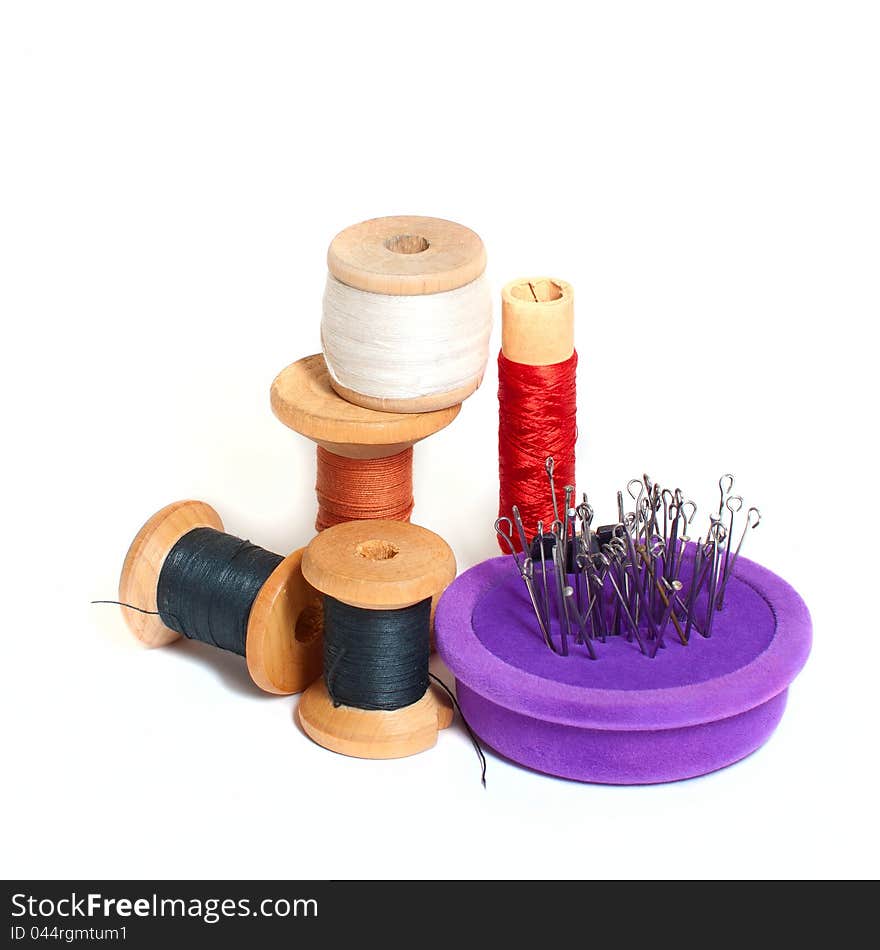 Group of spools with thread and needle bed  on white