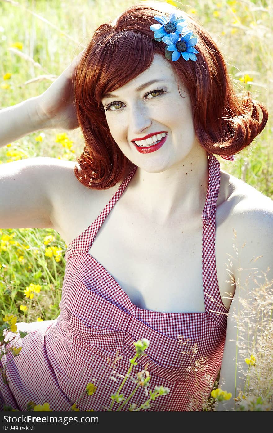 Beautiful red head pin up model sitting in a field. Beautiful red head pin up model sitting in a field