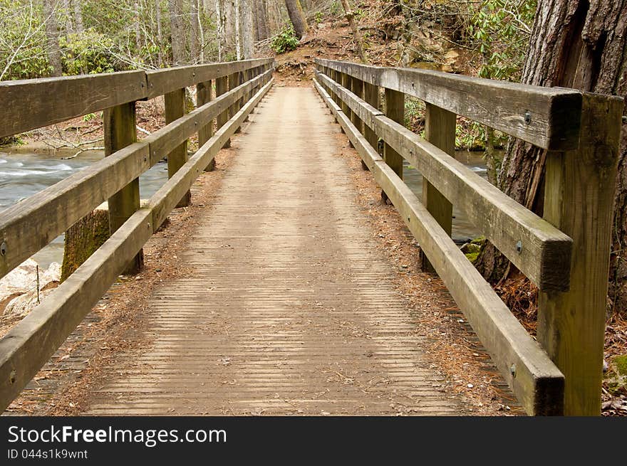 Wooden bridge over a white water stream.