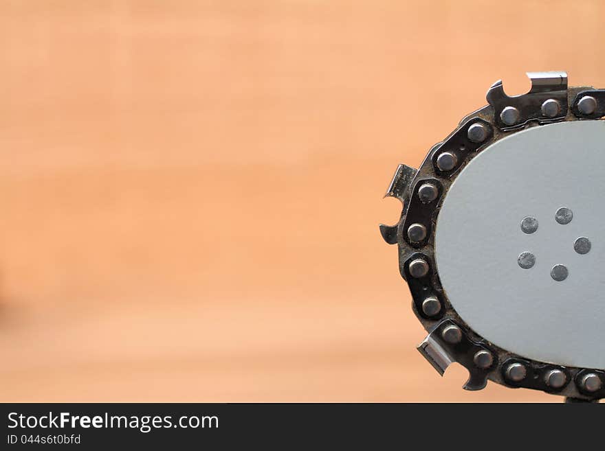 A side view of a used chainsaw bar and chain against a blurred wood back ground. Lots of room for ad copy.