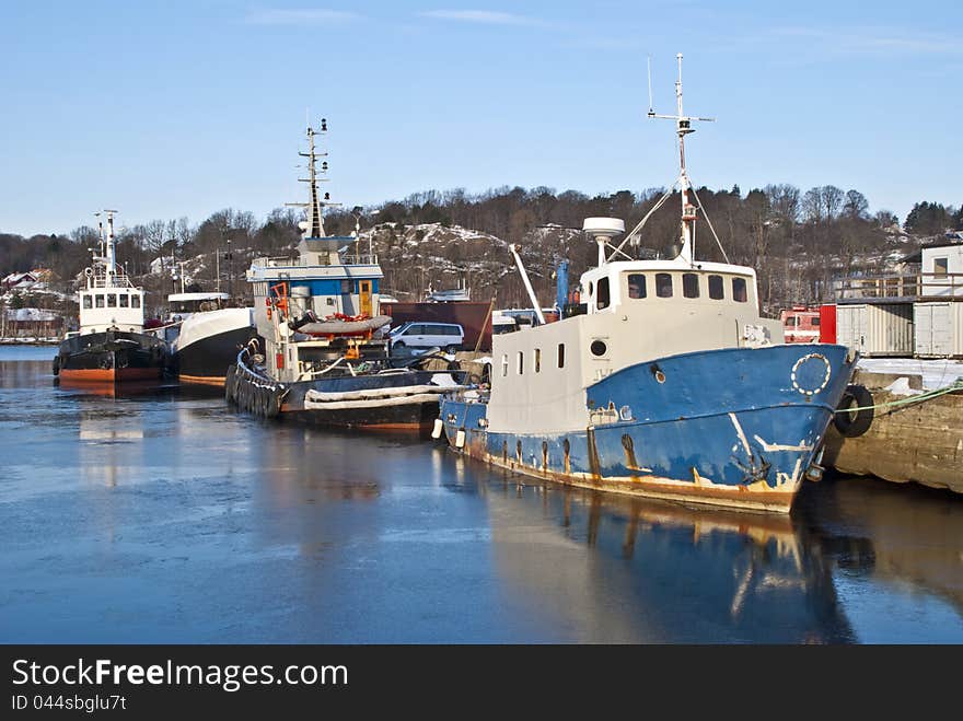 Fishing boats and tugboats moored to the docks at the port of Halden. Fishing boats and tugboats moored to the docks at the port of Halden.