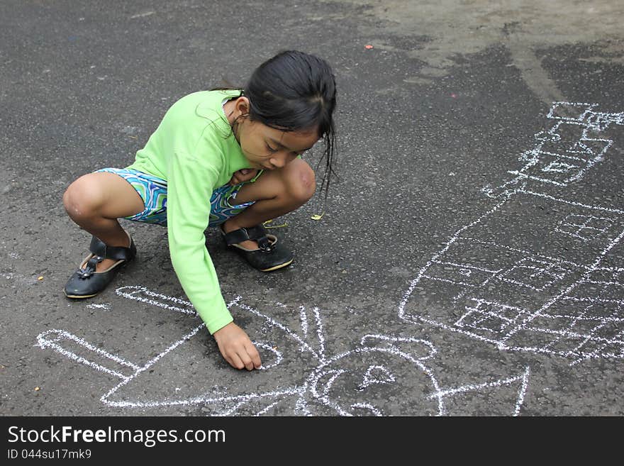 A female children was drawing on the street. A female children was drawing on the street.