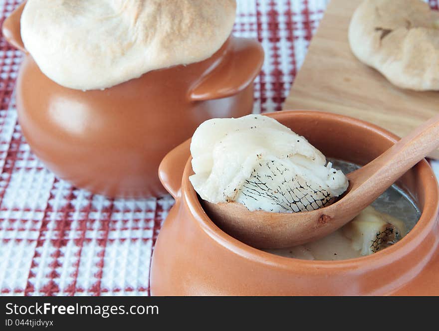 Fish baked with bacon in a pot under wheat flat cake