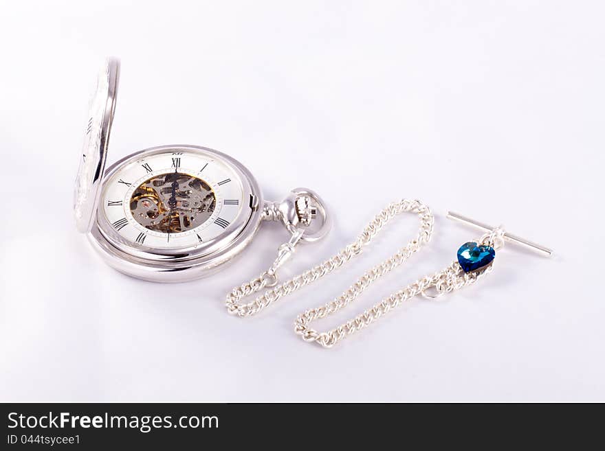 A silver pocketwatch and chain set against a white background. A silver pocketwatch and chain set against a white background.