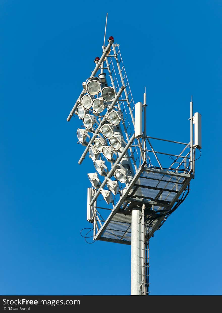 Stadium floodlight tower over blue sky