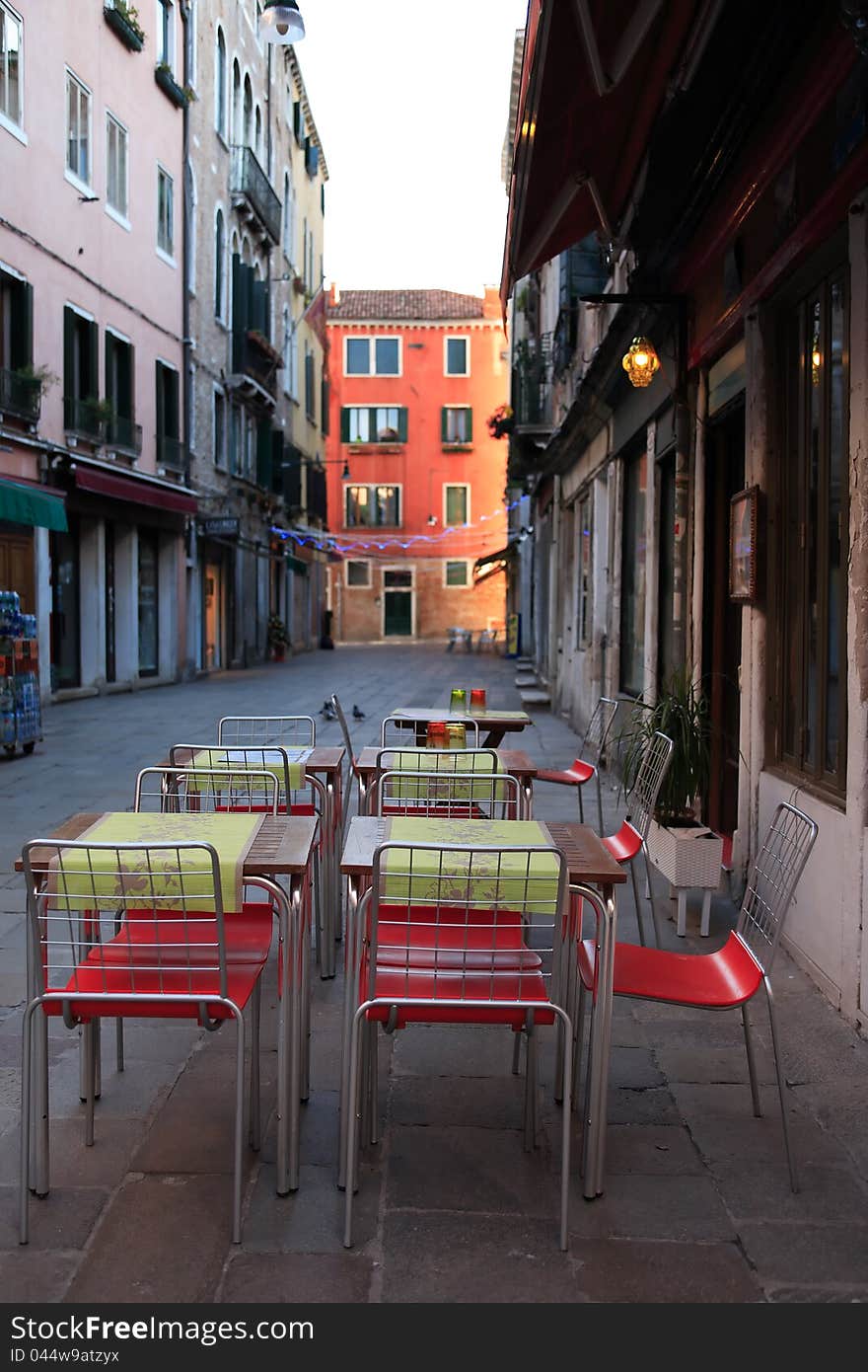 Urban scene. Few tables and chairs on narrow European street. Urban scene. Few tables and chairs on narrow European street