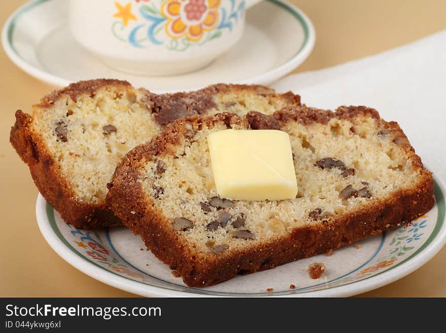 Two slices of nut bread with butter on a plate. Two slices of nut bread with butter on a plate