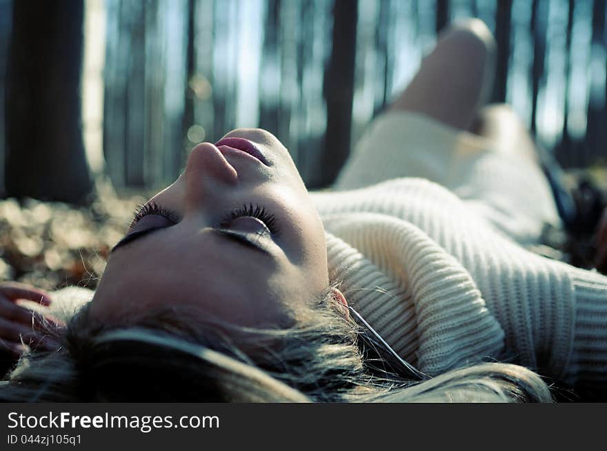 Beautiful blonde girl lying on leaves in a forest of poplars