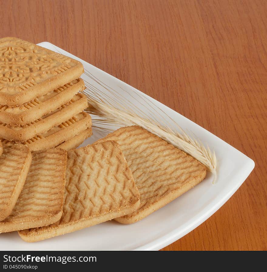 Fresh sweet biscuits on a plate of wheat spikelet