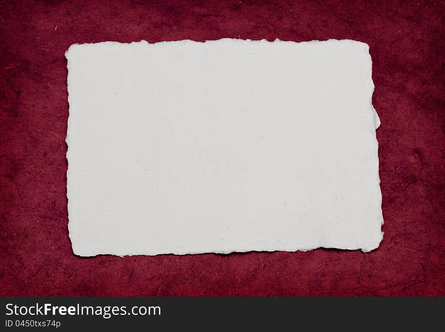 A torn piece of paper on a rough red background, perfect for a romantic invitation.