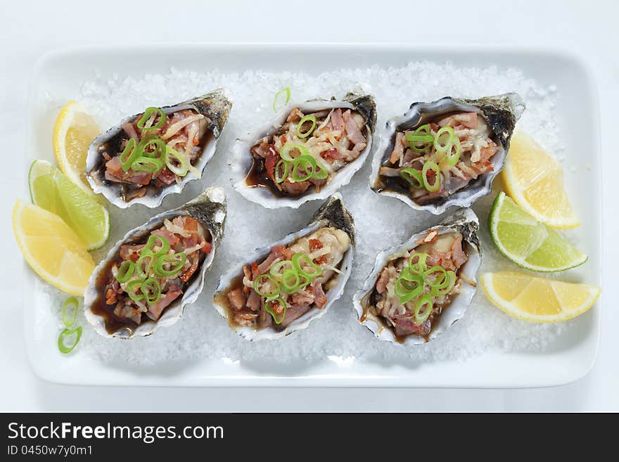 Oven baked oysters kilpatrick on a bed of rocksalt with lemon and lime. Oven baked oysters kilpatrick on a bed of rocksalt with lemon and lime