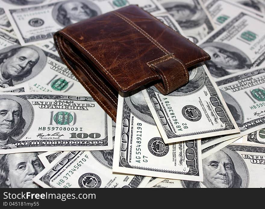 Leather purse lying among the one hundred dollar notes on white background. Leather purse lying among the one hundred dollar notes on white background