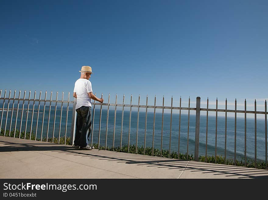 Senior man standing above the ocean looking out to sea