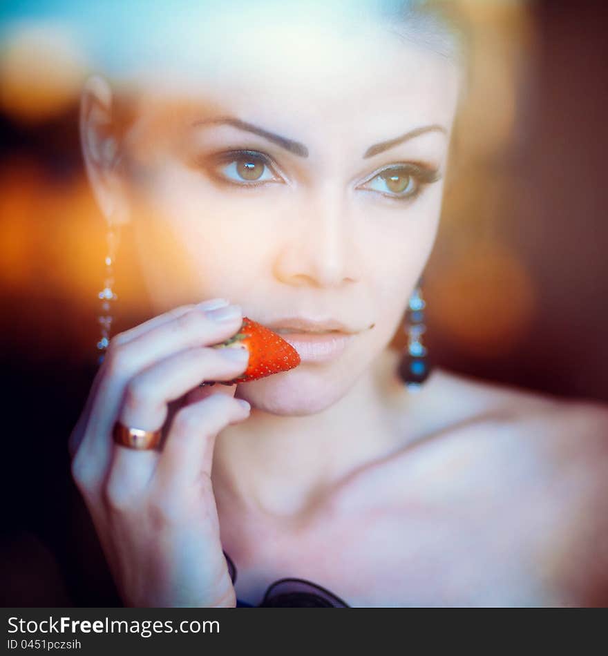 Portrait of a beautiful woman with strawberry in her hand