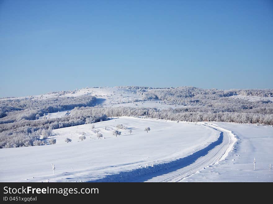 A winter scenery in the mountains with a road dug in high snow. A winter scenery in the mountains with a road dug in high snow