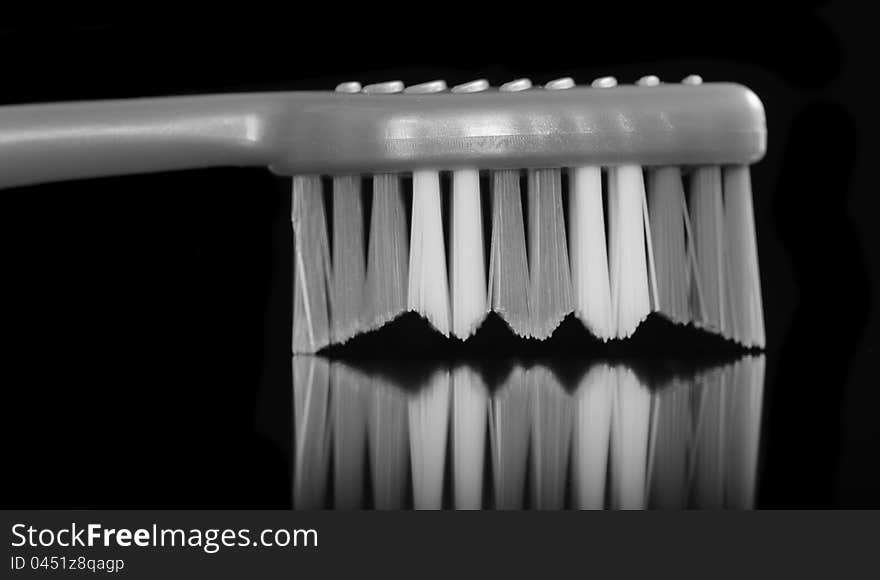 A monochrome image of a toothbrush with bristles down on a black background. A monochrome image of a toothbrush with bristles down on a black background