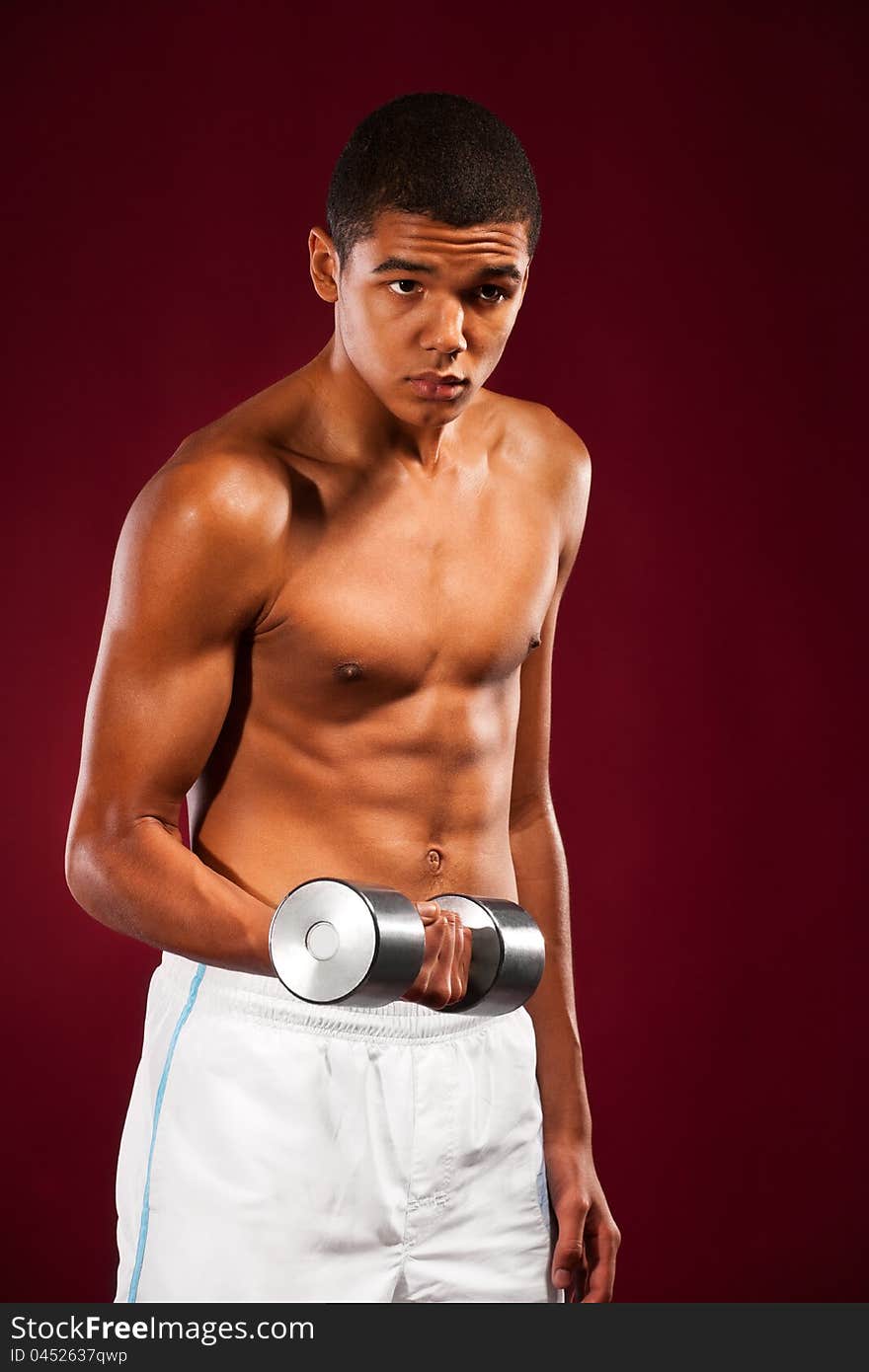 Young fit man lifting dumbell, studio shoot