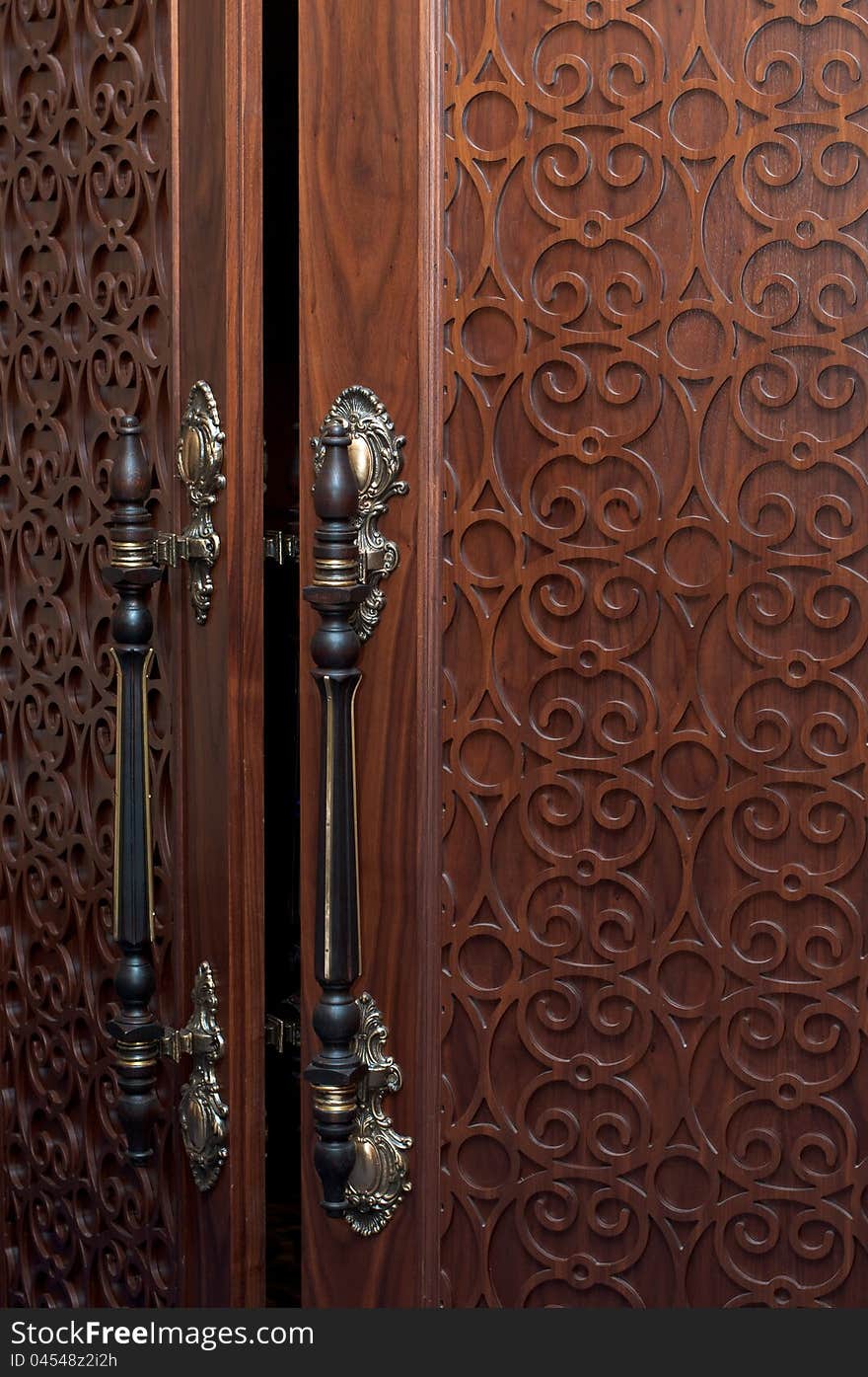 Handles on the old wooden door with carving. Handles on the old wooden door with carving