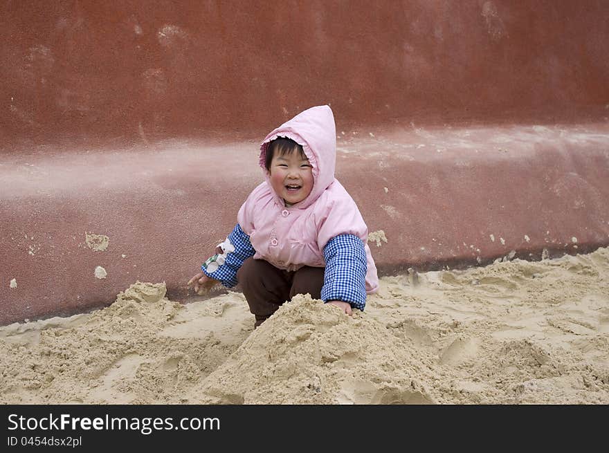 A happy girl is playing sand