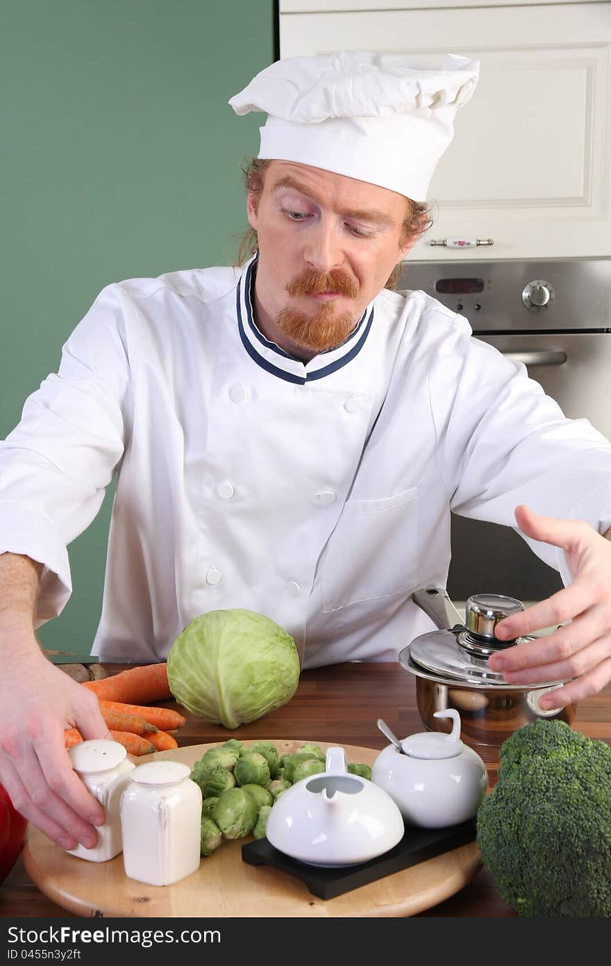 Funny young Chef takes the salt, preparing lunch in kitchen. Funny young Chef takes the salt, preparing lunch in kitchen