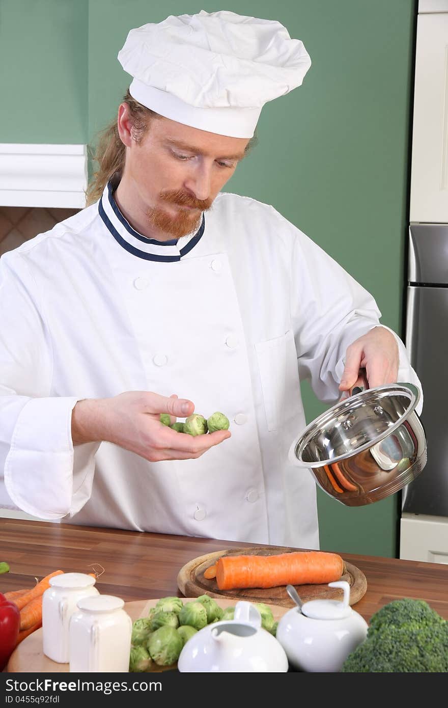 Young Chef with Brussels sprouts, preparing lunch in kitchen