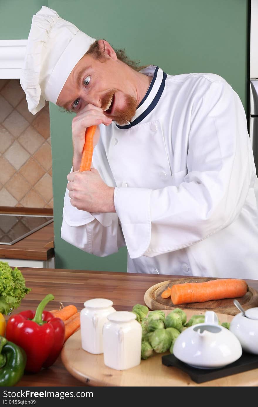 Funny young chef with carrot, preparing lunch in kitchen. Funny young chef with carrot, preparing lunch in kitchen