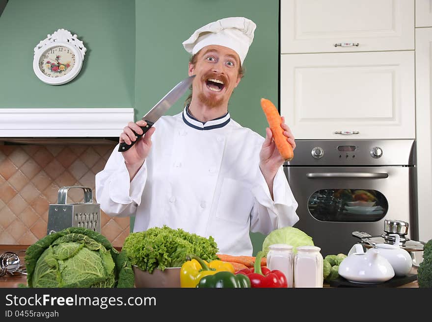 Funny young chef with carrot, preparing lunch in kitchen. Funny young chef with carrot, preparing lunch in kitchen