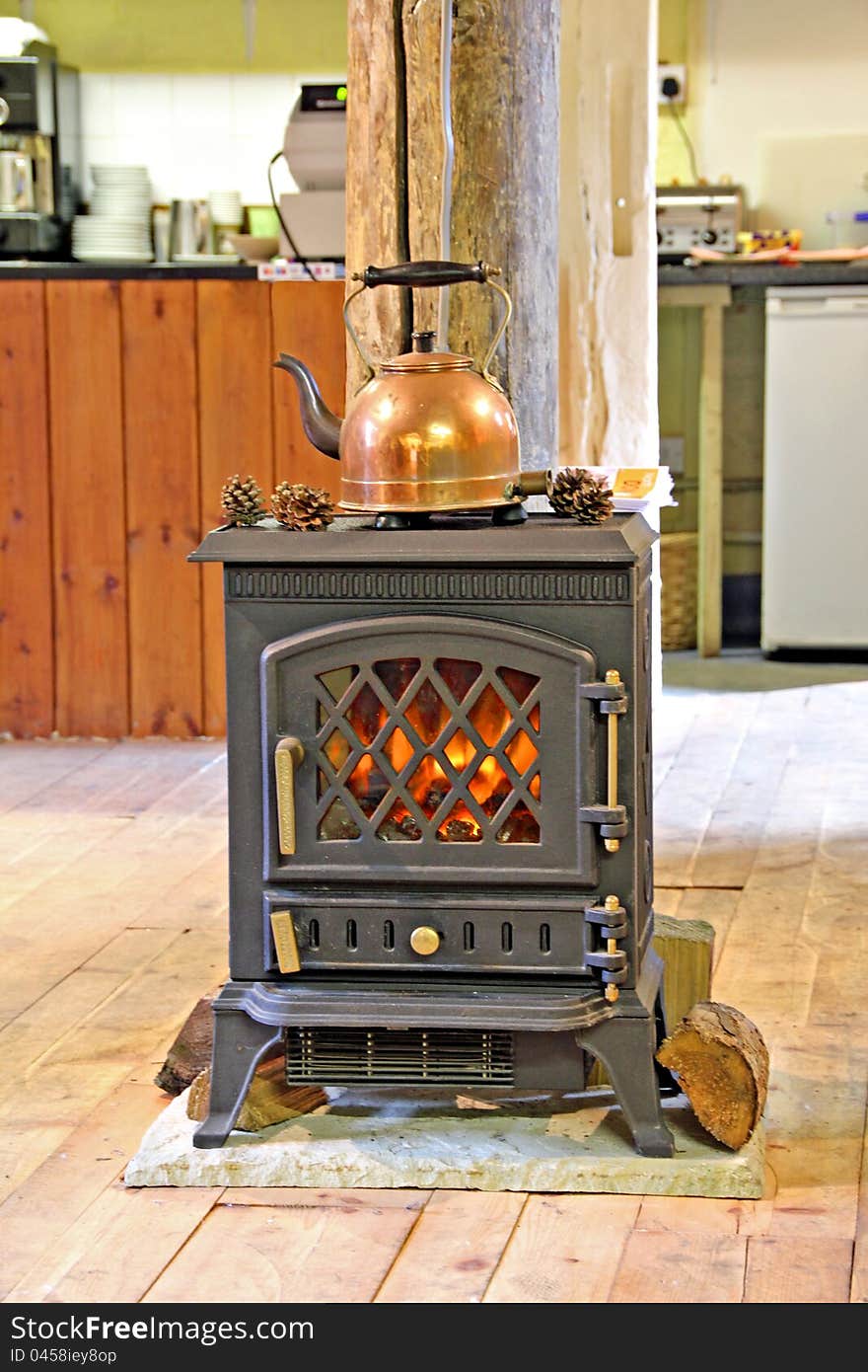 Photo of a copper kettle resting on top of a fire inside a country tea room. Photo of a copper kettle resting on top of a fire inside a country tea room.