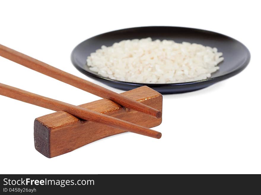 Wooden chopsticks and a black plate with rice on a white background. Wooden chopsticks and a black plate with rice on a white background