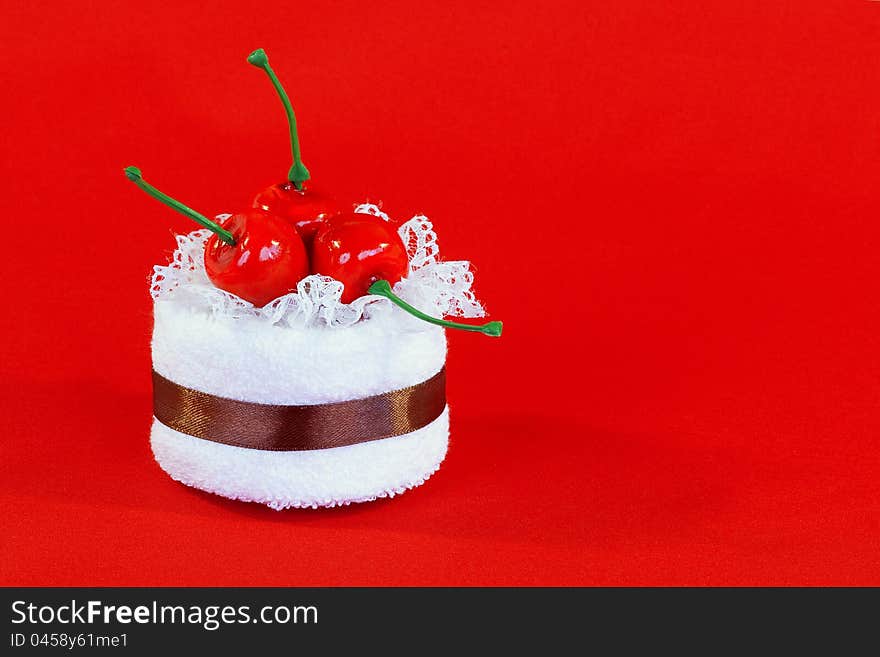 Rolled up towel with toy cherries on red background. Rolled up towel with toy cherries on red background