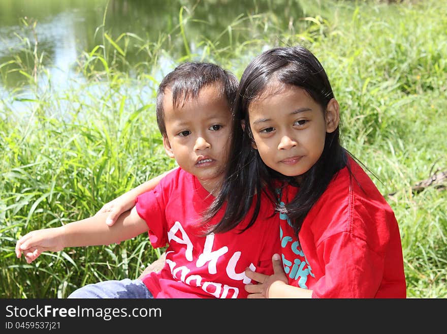 Little girl and her young brother were sitting at the edge of the lake.