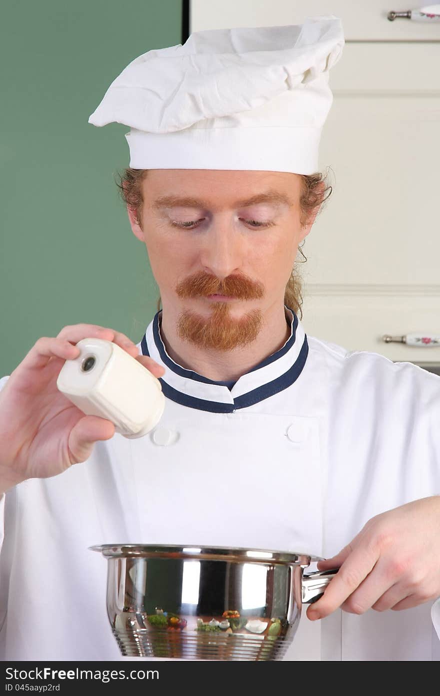 Young chef add salt in the pot, preparing lunch. Young chef add salt in the pot, preparing lunch