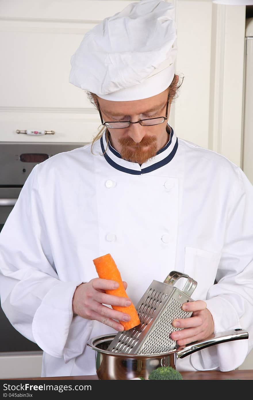 Young chef with carrot, preparing lunch in kitchen. Young chef with carrot, preparing lunch in kitchen