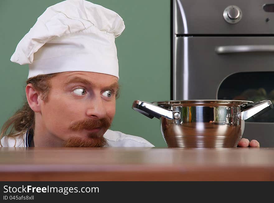 Funny young chef strange looking at pot