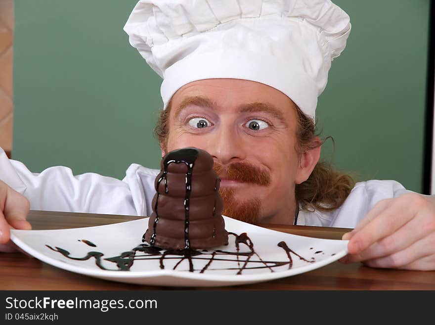 Funny young chef strange looking at piece of cake with chocolate sauce