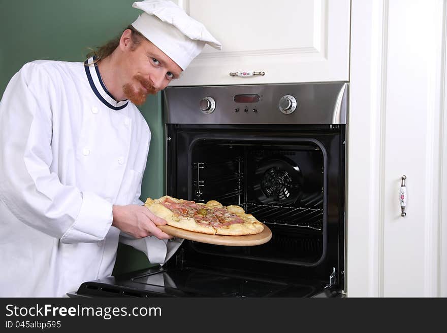 Young chef with italian pizza in kitchen