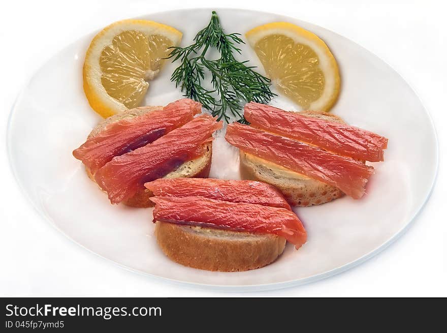 Sandwiches from a fillet red fish greens and a lemon on a plate on a white background