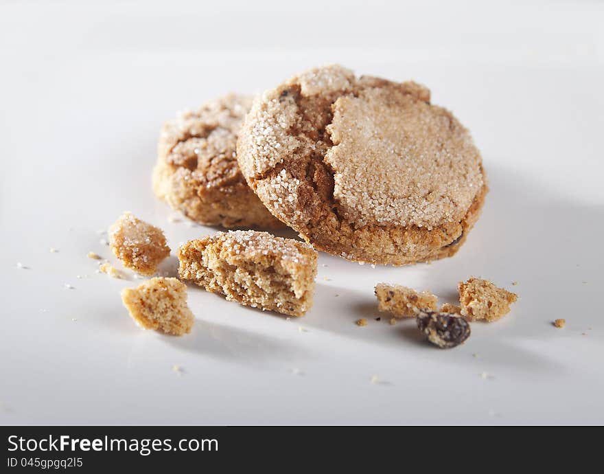 Two ginger cookies with risins and crumbs on the gray