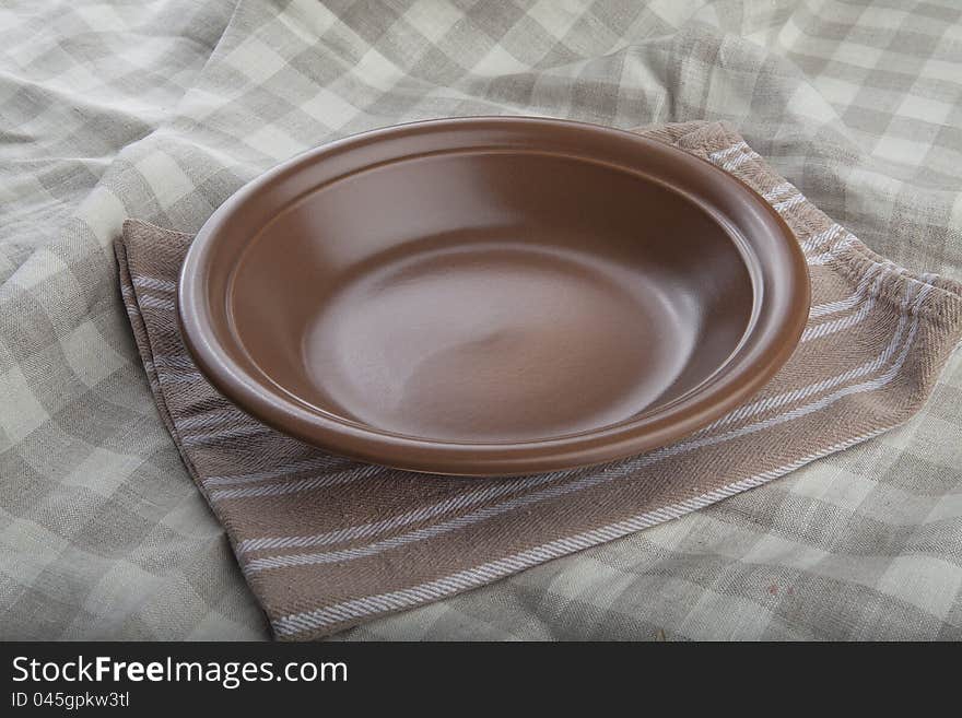 Empty brown bowl ob the striped linen napkin